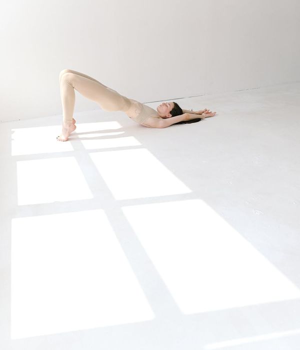 Woman in a flowing yoga pose in a bright, minimalist studio.